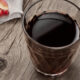 Glass of red wine on a weathered wooden table with pomegranate seeds on a white napkin in the corner on the left.