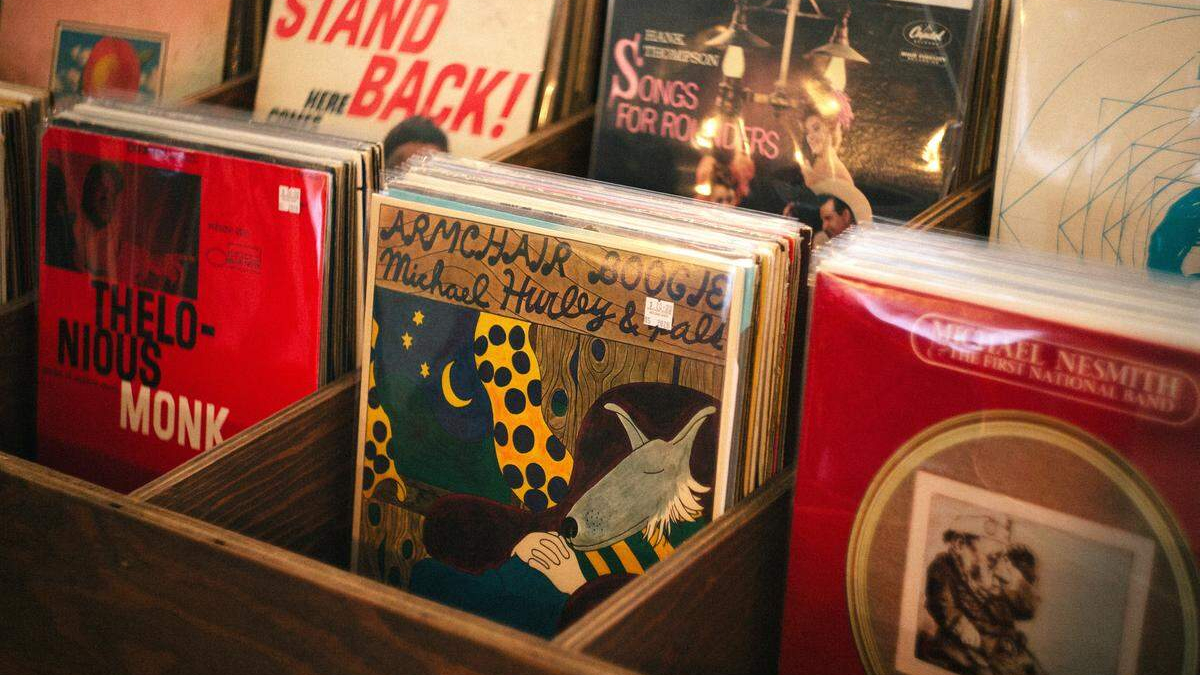 Close-up of wooden bins filled with colorful vinyl records in a record shop, with a bright red Thelonious Monk album visible on the left.
