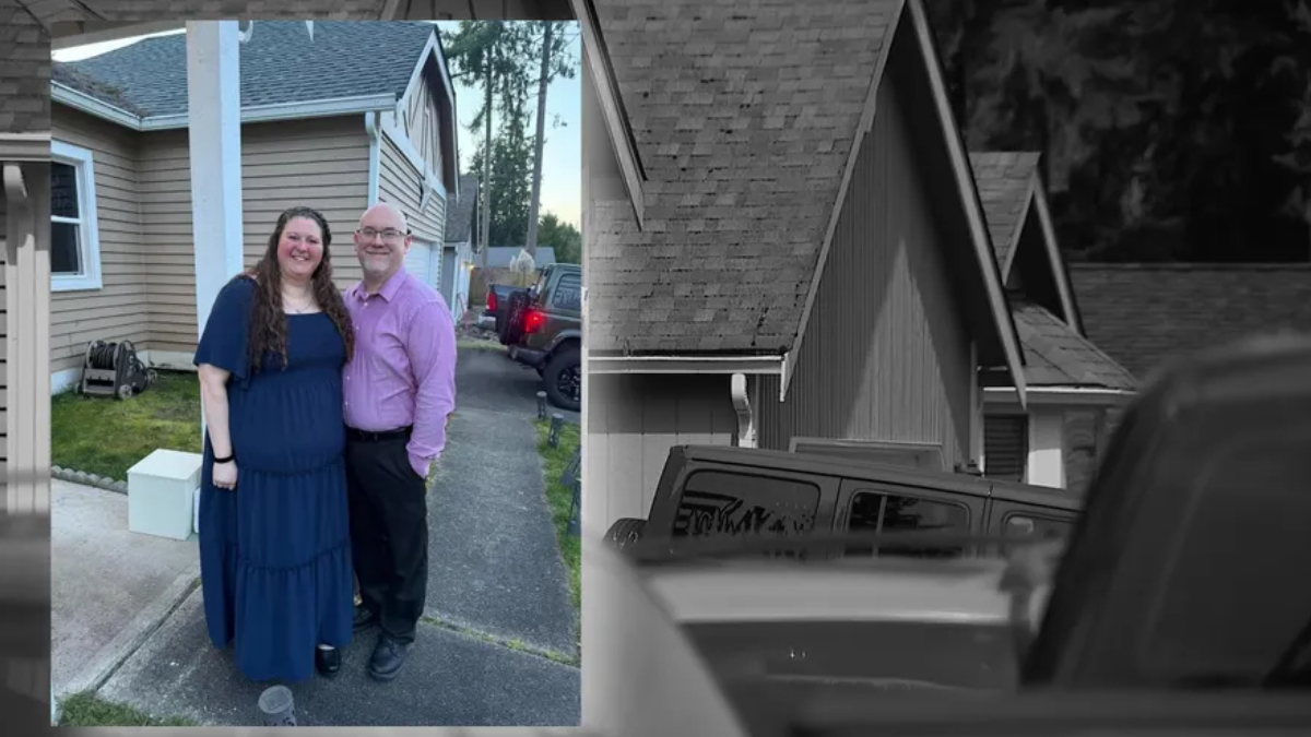 Smiling couple standing together in a driveway outside a beige house; woman in a blue dress, man in a purple shirt and dark pants.