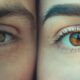 Close-up of two brown eyes side by side, one squinting on the left and the other wide open on the right, showing lashes and skin texture.
