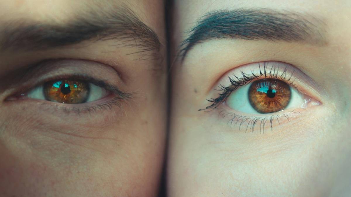 Close-up of two brown eyes side by side, one squinting on the left and the other wide open on the right, showing lashes and skin texture.