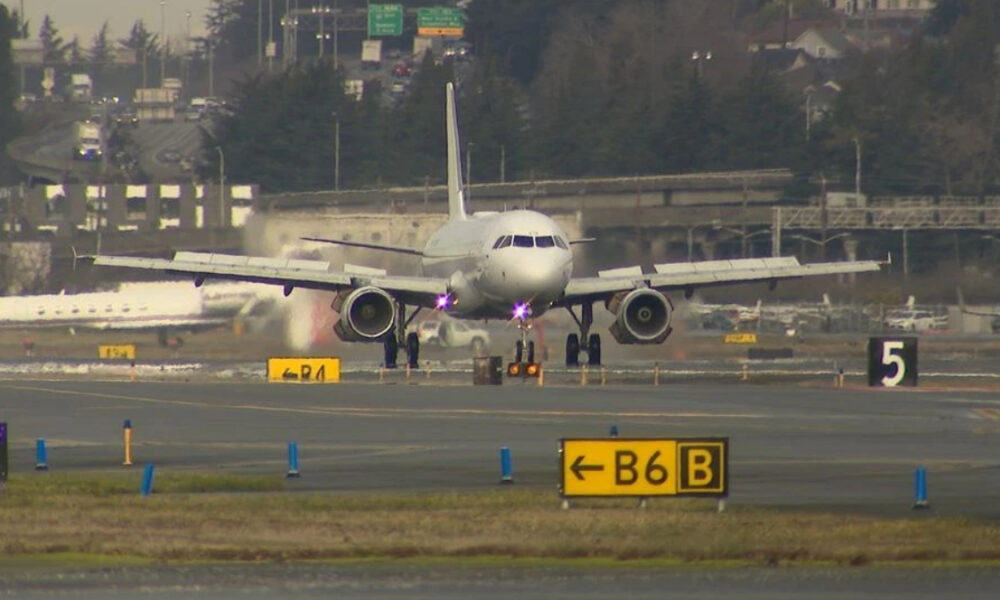 Passenger jet taxiing on the taxiway toward the runway, with yellow B6B and other runway signs in the foreground.