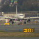 Passenger jet taxiing on the taxiway toward the runway, with yellow B6B and other runway signs in the foreground.
