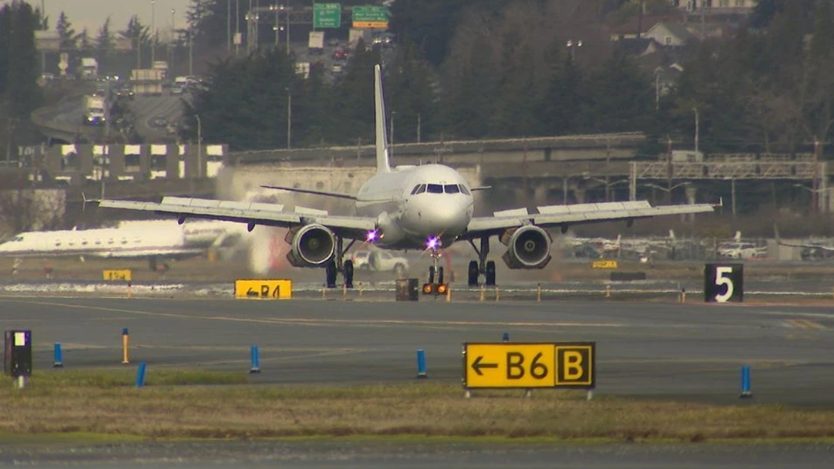 Passenger jet taxiing on the taxiway toward the runway, with yellow B6B and other runway signs in the foreground.