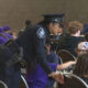 Uniformed police officer bends to help a child during a crowded community chess event in a large hall.