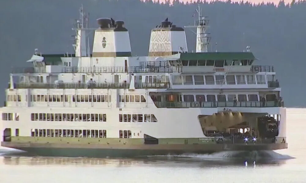 Large white passenger ferry with multiple decks sailing on calm water, rear vehicle loading ramp open for cars.
