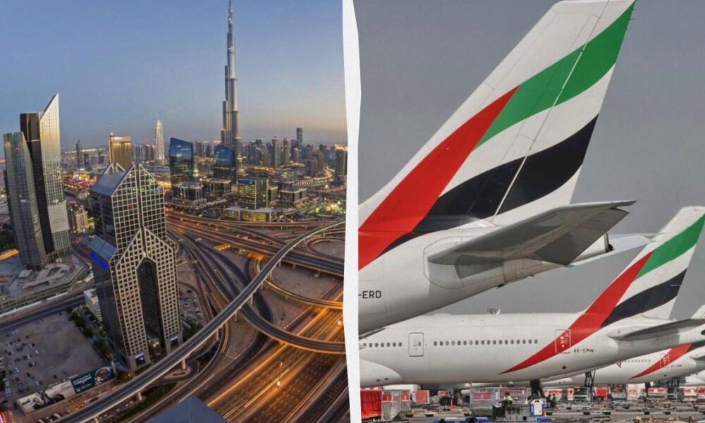 Dubai skyline at dusk with complex highway interchanges on the left; Emirates aircraft tails on the right.