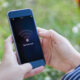 Smartphone held outdoors showing a 'No Network' message on the screen with a Wi‑Fi icon in a green, natural background.