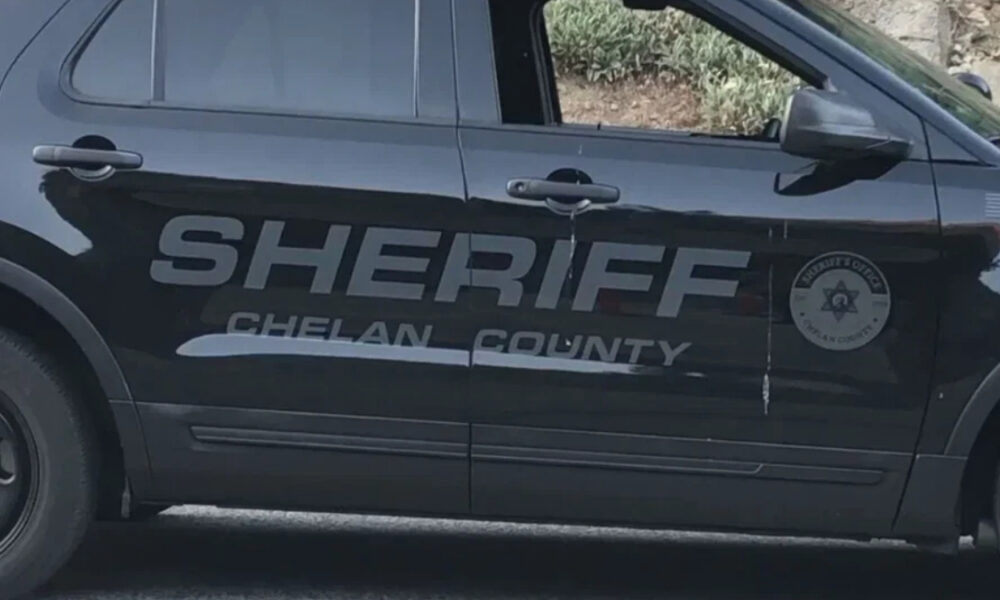 Side view of a Chelan County Sheriff SUV with large 'SHERIFF' lettering and a circular sheriff badge on the door