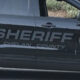 Side view of a Chelan County Sheriff SUV with large 'SHERIFF' lettering and a circular sheriff badge on the door