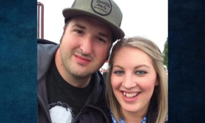 Smiling man and woman taking a selfie outdoors, facing the camera with heads close together.
