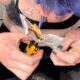 Person with blue hair and teal nails heats foil-wrapped material with a lighter held in one hand.