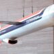 Hanging display model of a Tomahawk aircraft with red, white, and blue livery labeled Tomahawk and General Dynamics, suspended from cables against a stone wall