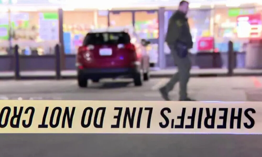 Crime scene tape in the foreground reads 'DO NOT CROSS' (inverted); blurred man and a red SUV seen near a storefront.