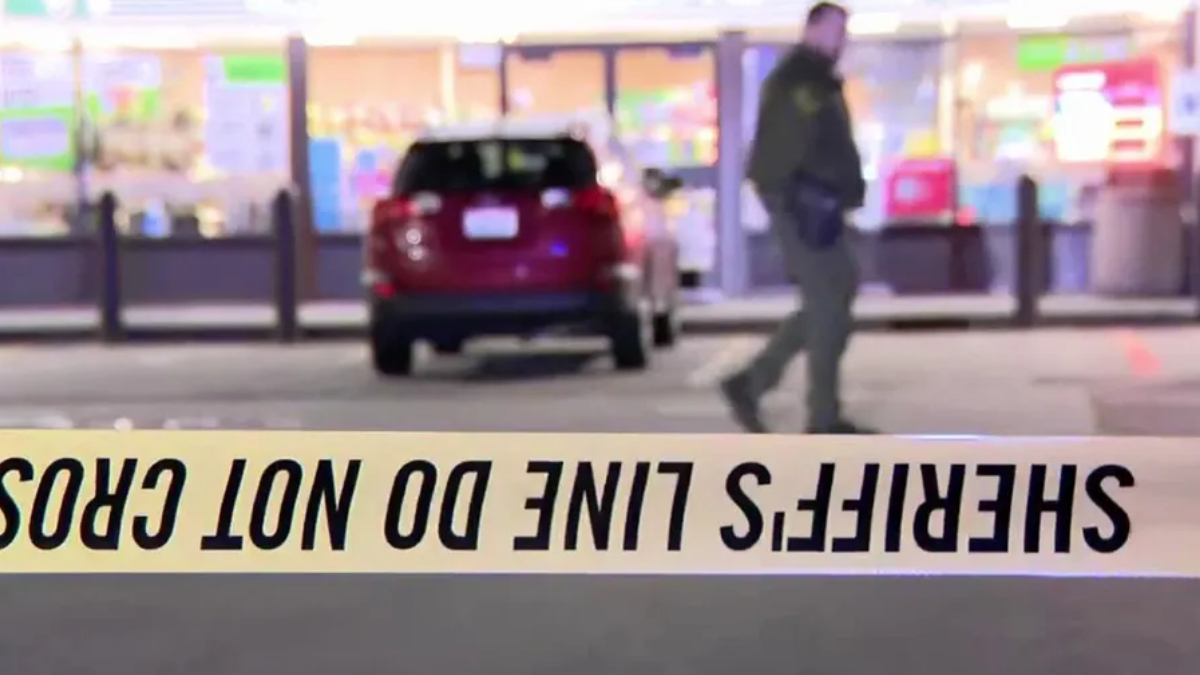 Crime scene tape in the foreground reads 'DO NOT CROSS' (inverted); blurred man and a red SUV seen near a storefront.