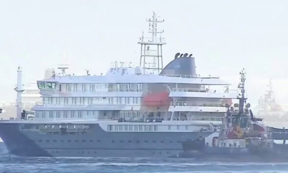 Large luxury yacht being assisted by a tugboat on calm sea