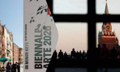 A split image: left shows a city street with a poster reading 'In Minor Keys' and 'Bienne Art 2020'; right view through a window showing a red clock tower and silhouettes of people in a plaza at dusk.