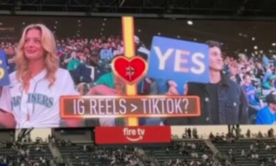 Stadium jumbotron shows two fans holding blue YES signs, a central heart emblem, and the caption 'IG REELS > TIKTOK?'