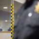 Glass window with a sheriff badge decal and security stickers; a blurred police officer is visible on the right.