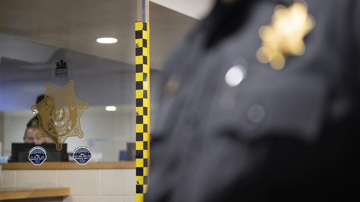 Glass window with a sheriff badge decal and security stickers; a blurred police officer is visible on the right.