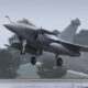 Two-seat military fighter jet lifting off the wet runway in overcast weather, gear still extended.