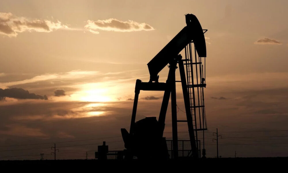 Silhouetted oil pumpjack against an orange sunset on a flat horizon