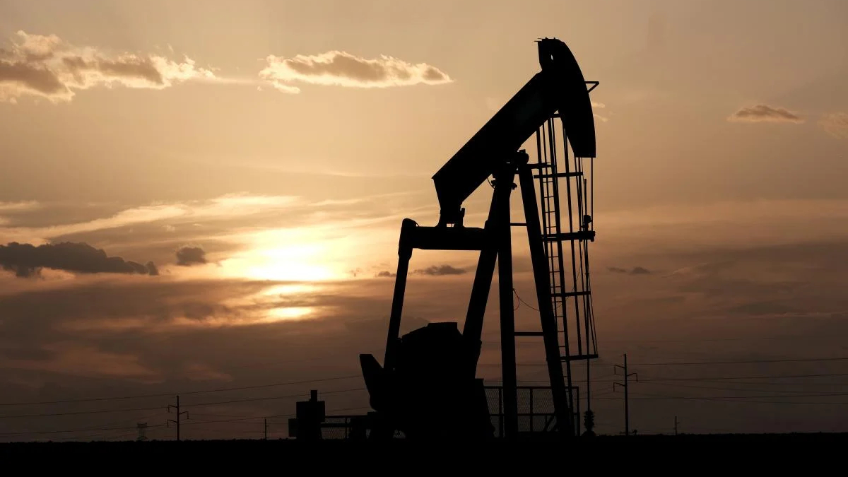 Silhouetted oil pumpjack against an orange sunset on a flat horizon