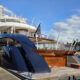 Large luxury yacht docked at a marina under a blue sky, name Launchpad visible on the stern area