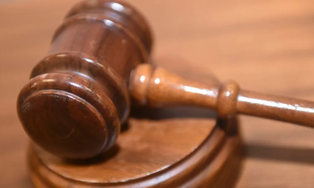 Wooden judge's gavel resting on a sound block on a courtroom table.
