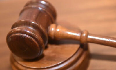 Wooden judge's gavel resting on a sound block on a courtroom table.