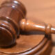 Wooden judge's gavel resting on a sound block on a courtroom table.