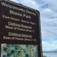 Park sign that reads: Welcome to Denny Blaine Park; hours 6am–10pm; clothing required west of fence (Area 1); clothing optional east of fence (Areas 2+3).