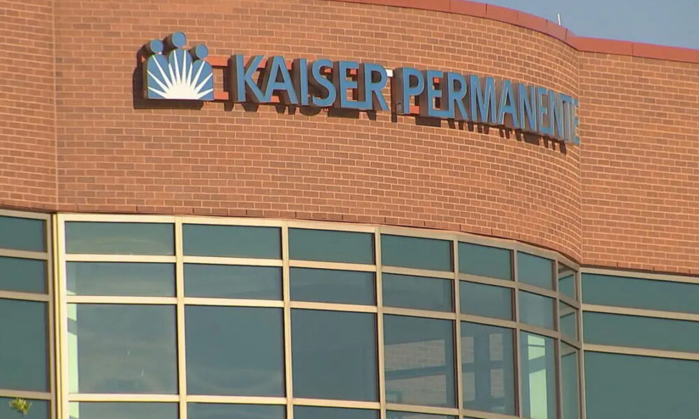 Facade of a Kaiser Permanente medical building with a brick exterior and large glass windows beneath a curved wall.