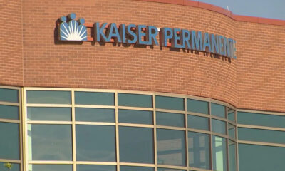Facade of a Kaiser Permanente medical building with a brick exterior and large glass windows beneath a curved wall.