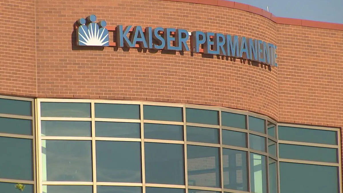 Facade of a Kaiser Permanente medical building with a brick exterior and large glass windows beneath a curved wall.