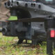 Close-up of a gray quadcopter drone on grass, revealing its multi-lens camera and landing gear in the foreground.