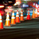 Nighttime roadwork scene with orange traffic cones lining a construction zone and blurred cars in motion as they pass by.
