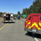 Emergency responders on a highway with a backup of vehicles, a red fire/ambulance truck, and a helicopter on the road nearby.