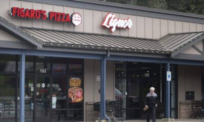 Front of a strip-mall pizza shop with Figaro's Pizza and Liquor signs; an elderly man exits carrying a bag.