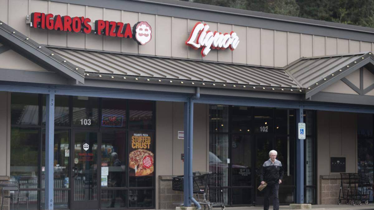 Front of a strip-mall pizza shop with Figaro's Pizza and Liquor signs; an elderly man exits carrying a bag.