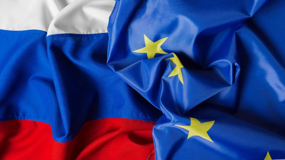 Russian flag partially draped over the European Union flag with yellow stars on blue field and red stripe visible at the bottom left