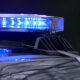 Blue flashing emergency lights on the roof of a police car, reflecting off the hood.
