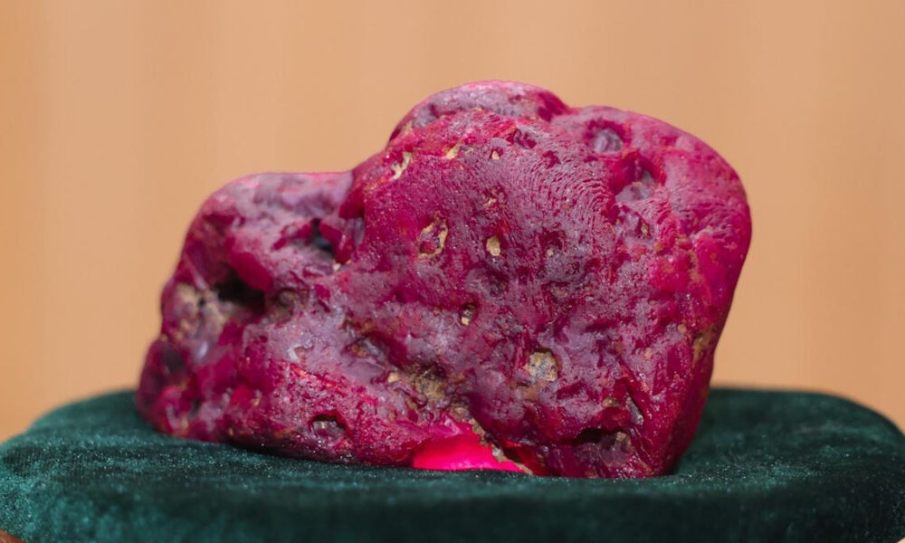 Large pink, porous rock candy-like specimen resting on dark green velvet surface.
