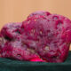 Large pink, porous rock candy-like specimen resting on dark green velvet surface.
