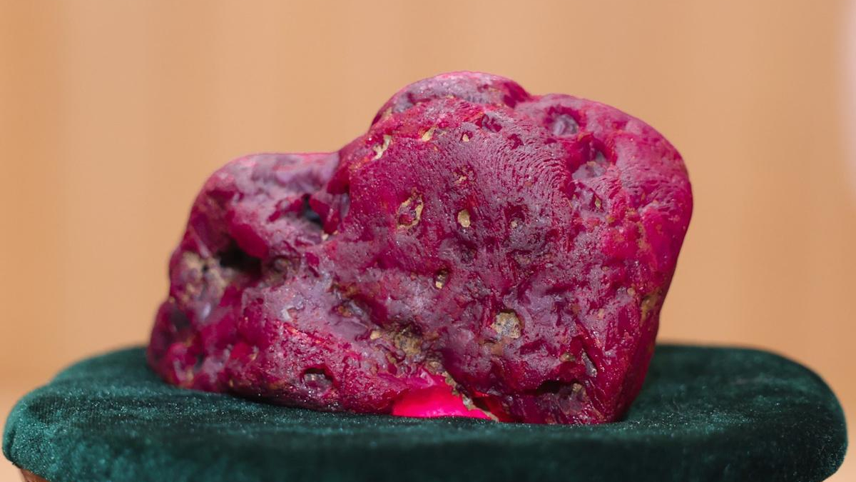Large pink, porous rock candy-like specimen resting on dark green velvet surface.
