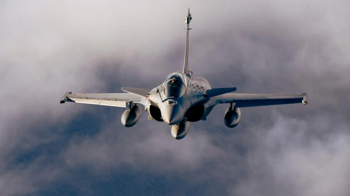 Front-facing fighter jet flying toward the camera through a cloudy sky down to the viewer's level.