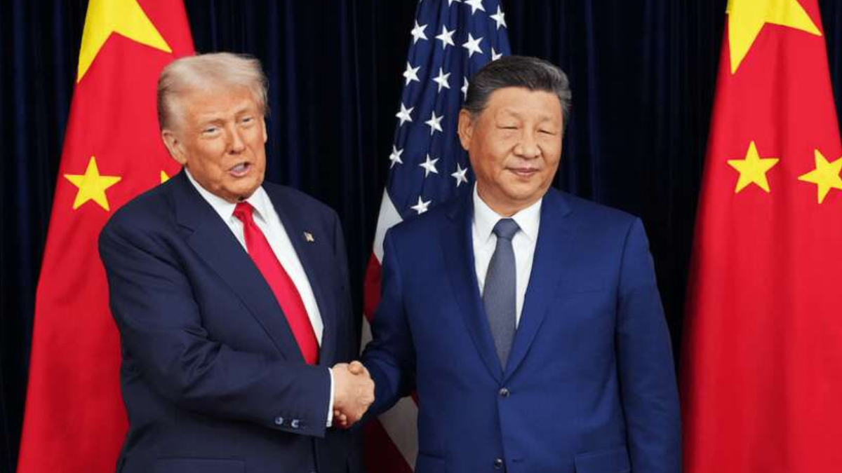 Two men in suits shake hands in front of US and China flags behind them.