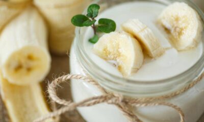 Creamy banana smoothie in a mason jar, topped with banana slices and a small green sprig.