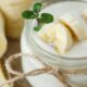 Creamy banana smoothie in a mason jar, topped with banana slices and a small green sprig.