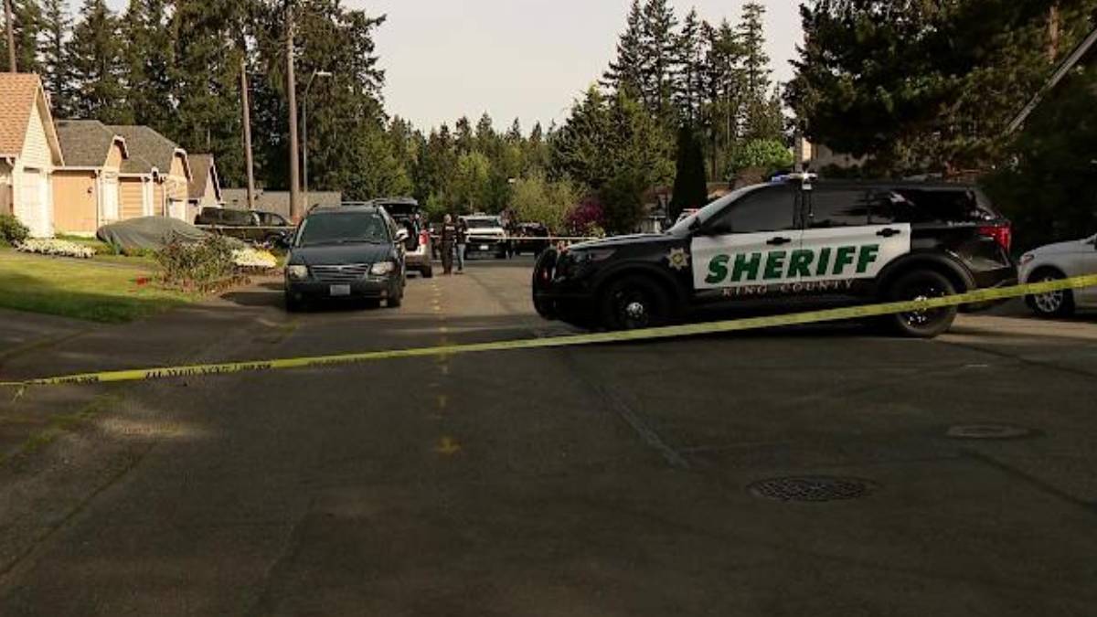 Sheriff patrol SUV blocks a residential street with yellow tape as investigators work in the background.